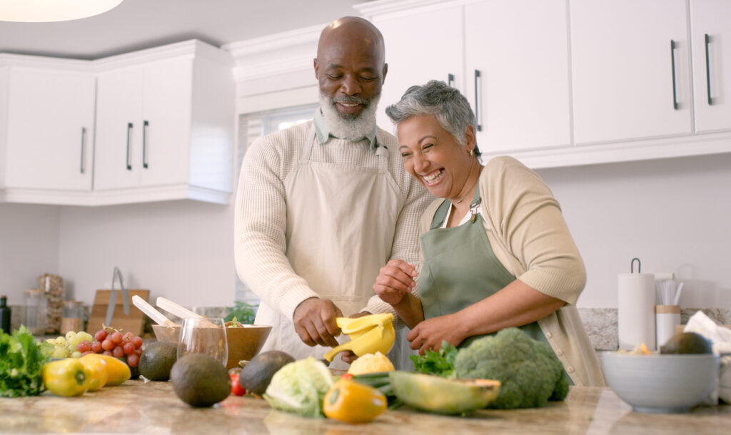 Cooking, kitchen and senior with a black couple laughing while preparing a meal together in their house. Food, health and funny with a mature man and woman having fun or bonding in a retirement home