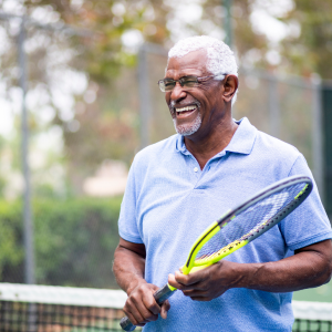elderly person smiling and playing tennis