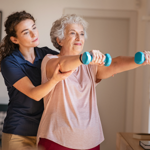 Elderly person using workout weights with guidance from another person